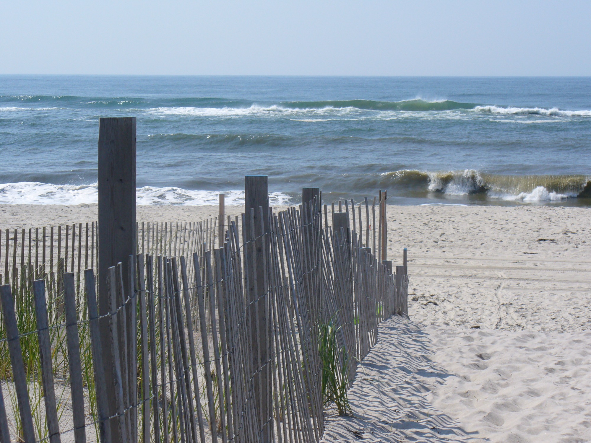 Sand fence running down to the ocean beach at Saltaire, surf beyond